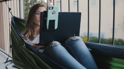 Woman in hammock with a phone in a Device Caddy on a laptop